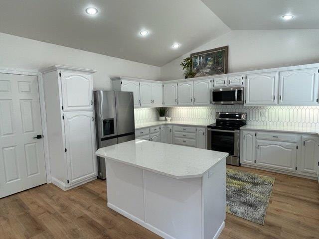 kitchen featuring stainless steel appliances, tasteful backsplash, wood finished floors, and light countertops