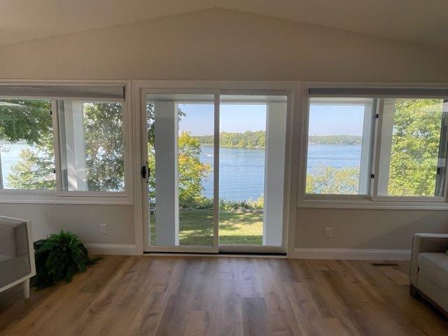 unfurnished sunroom with a water view, visible vents, and vaulted ceiling