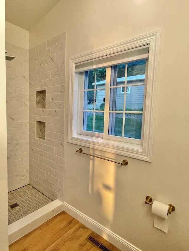 full bathroom with a stall shower, baseboards, visible vents, and wood finished floors