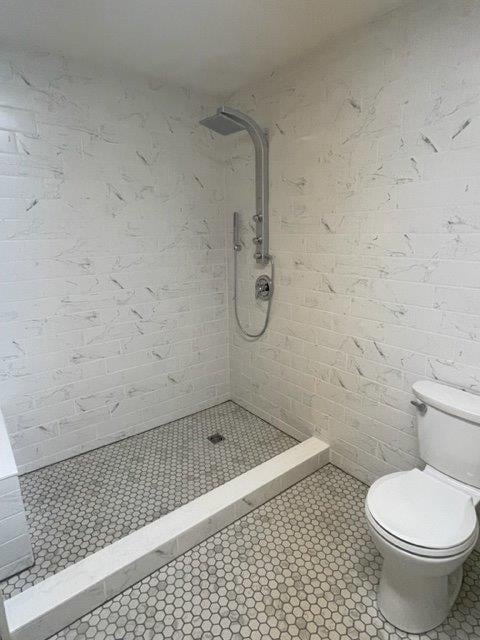 bathroom with a stall shower, toilet, and tile patterned floors