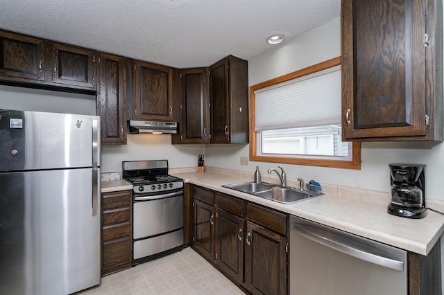 kitchen with under cabinet range hood, dark brown cabinetry, light countertops, appliances with stainless steel finishes, and a sink