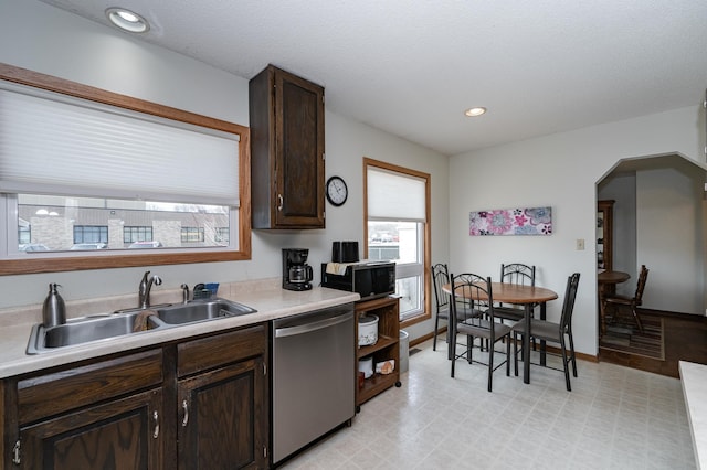 kitchen with a sink, arched walkways, dark brown cabinetry, black microwave, and dishwasher