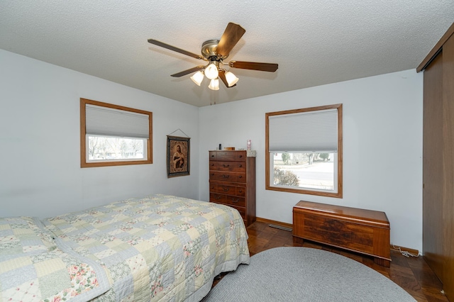 bedroom with visible vents, baseboards, a textured ceiling, and ceiling fan