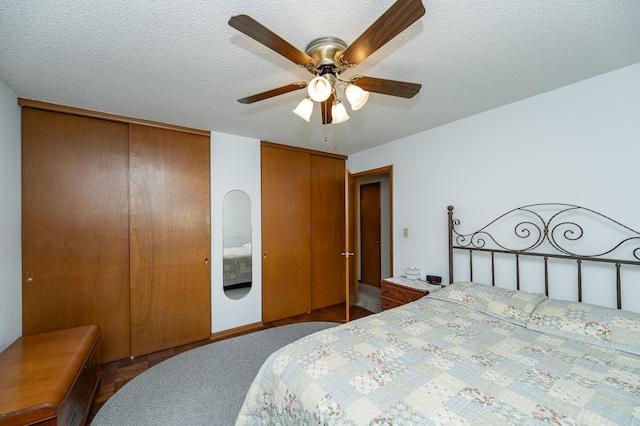 bedroom with two closets, ceiling fan, and a textured ceiling