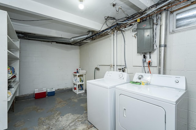 washroom with electric panel, concrete block wall, independent washer and dryer, and laundry area