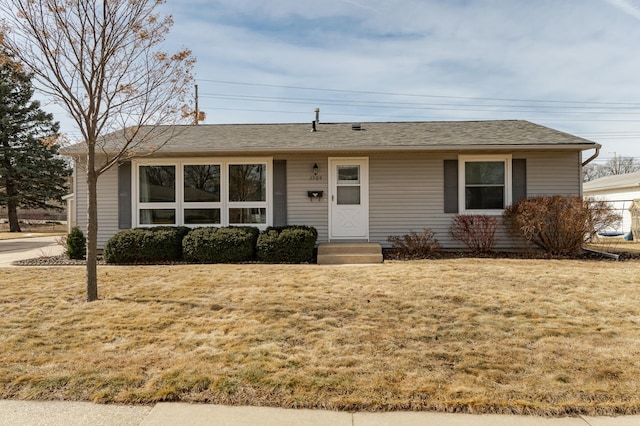 single story home featuring entry steps, a shingled roof, and a front lawn