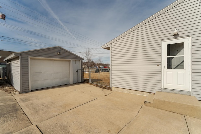 detached garage with concrete driveway and fence