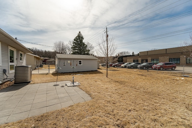 view of yard with an outbuilding, a patio, central AC, and fence