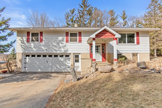 raised ranch featuring brick siding, a garage, and driveway