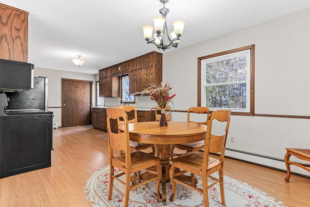 dining room with a notable chandelier, light wood-style floors, and a wainscoted wall