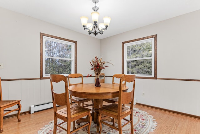 dining space with a baseboard heating unit, a notable chandelier, light wood-style flooring, and wainscoting