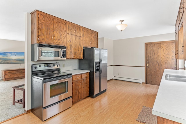 kitchen with light wood finished floors, a sink, stainless steel appliances, light countertops, and a baseboard heating unit