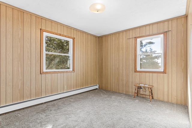 carpeted spare room with plenty of natural light, a baseboard heating unit, and wooden walls