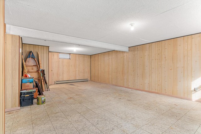 finished below grade area with tile patterned floors, wooden walls, baseboard heating, and a textured ceiling