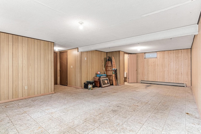 finished below grade area with baseboards, wood walls, a textured ceiling, tile patterned floors, and baseboard heating