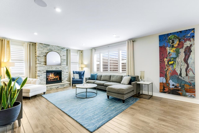 living room with a stone fireplace, recessed lighting, wood finished floors, and baseboards