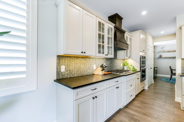 kitchen featuring tasteful backsplash, dark countertops, glass insert cabinets, and custom range hood