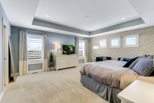 bedroom with visible vents, baseboards, a raised ceiling, and light colored carpet