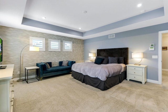 bedroom featuring a tray ceiling, recessed lighting, light colored carpet, visible vents, and baseboards