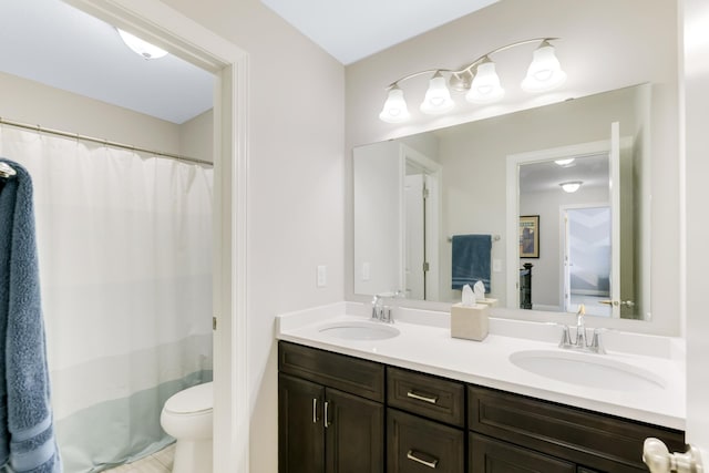 bathroom featuring double vanity, toilet, and a sink