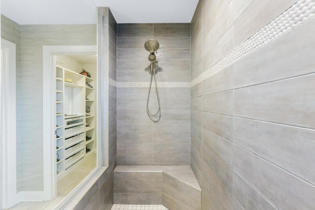 bathroom with a tile shower and a spacious closet