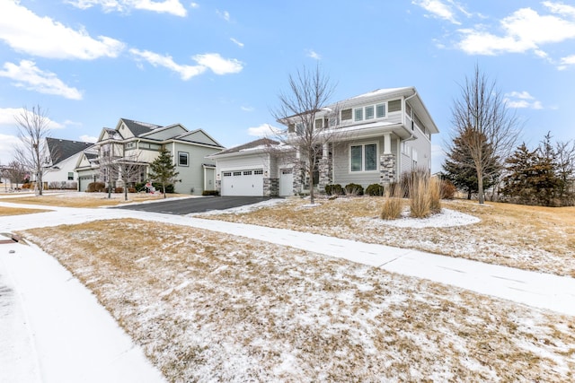 view of front of house featuring an attached garage, stone siding, driveway, and a residential view