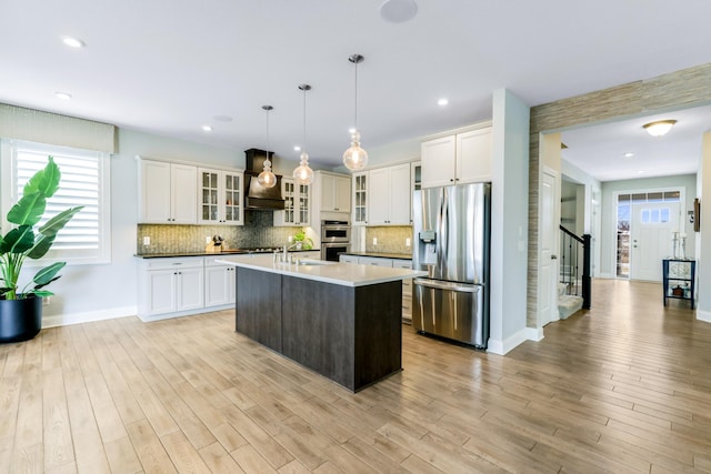 kitchen with plenty of natural light, appliances with stainless steel finishes, light wood-type flooring, and backsplash