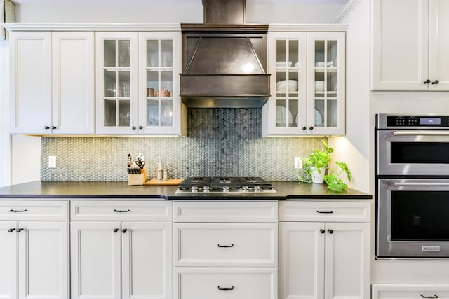 kitchen with stainless steel appliances, dark countertops, white cabinetry, and custom range hood