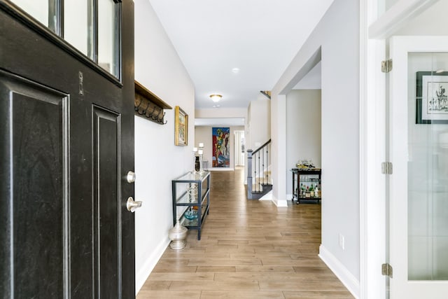 entrance foyer with light wood-style flooring, stairway, and baseboards