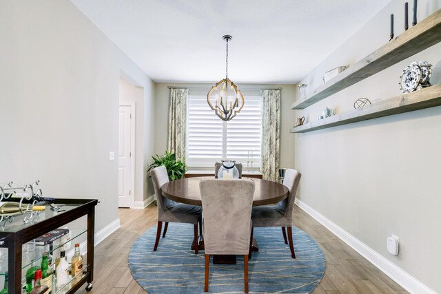 dining space with light wood finished floors, baseboards, and an inviting chandelier