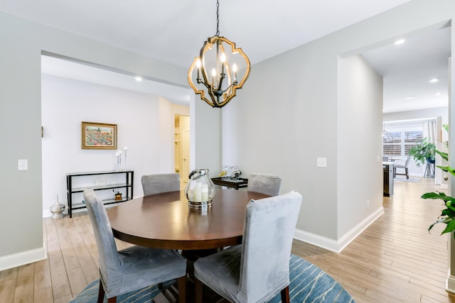 dining area featuring light wood-style floors, baseboards, and a notable chandelier