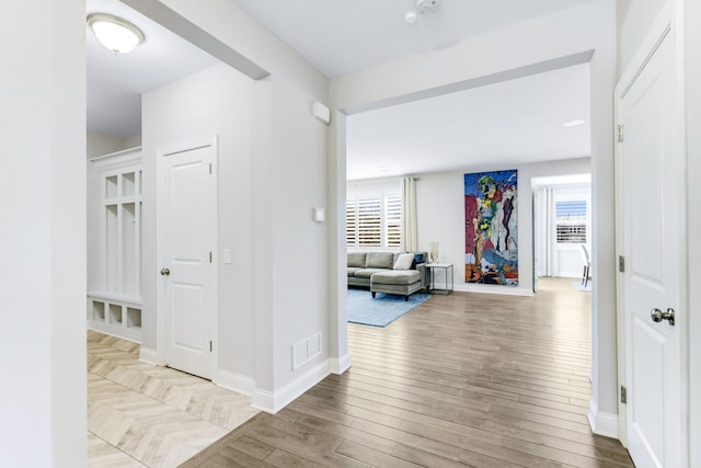 corridor featuring a wealth of natural light, visible vents, baseboards, and wood finished floors