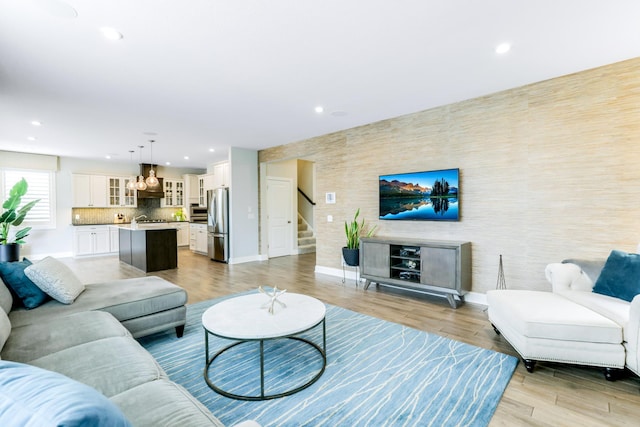 living room with stairs, recessed lighting, light wood-type flooring, and baseboards