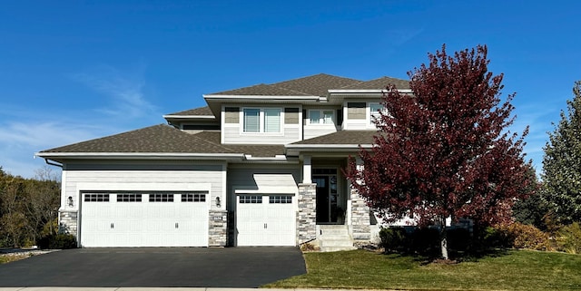 prairie-style house featuring an attached garage, aphalt driveway, and a front yard