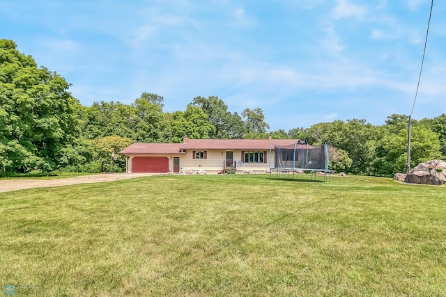 ranch-style home featuring a garage, driveway, a front lawn, and a trampoline