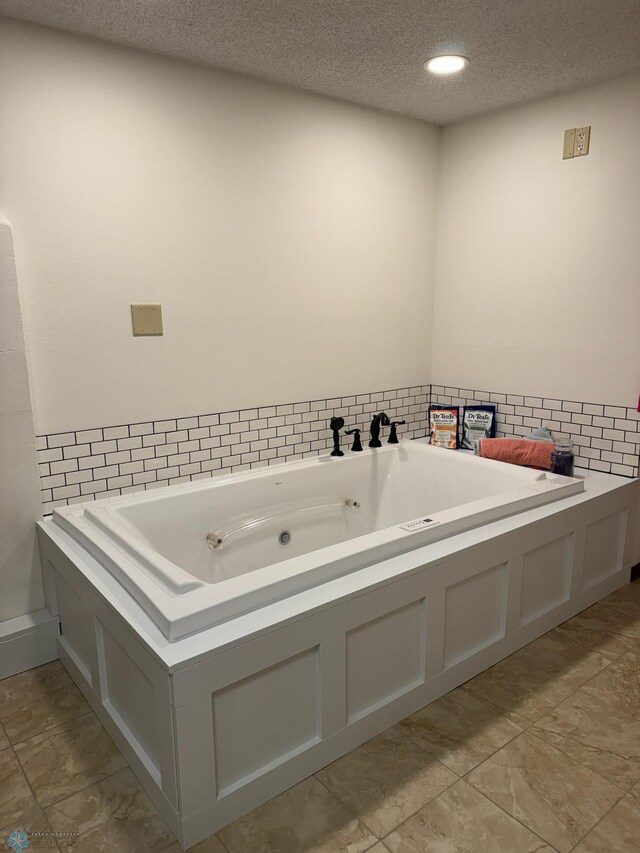 full bathroom with a textured ceiling and a tub with jets