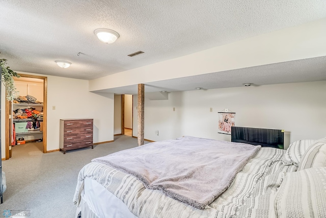 bedroom featuring a textured ceiling, visible vents, baseboards, a spacious closet, and a closet