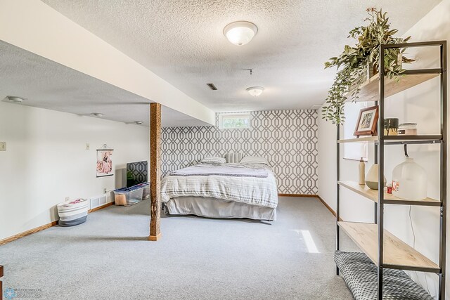 carpeted bedroom featuring visible vents, a textured ceiling, baseboards, and wallpapered walls