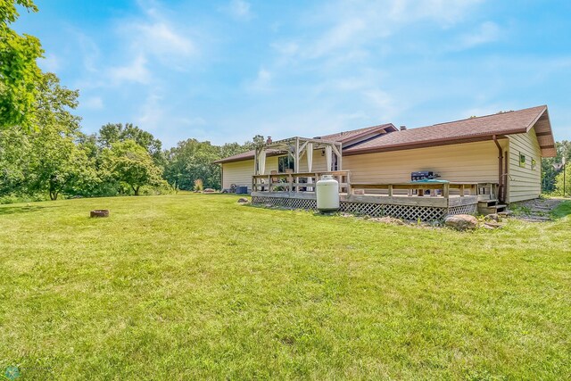 rear view of property featuring a deck and a lawn