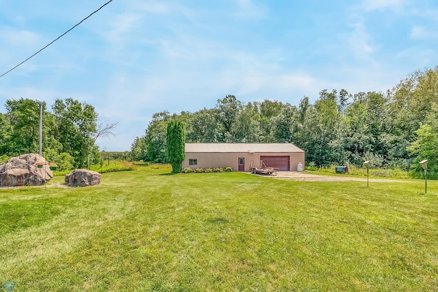 view of yard featuring driveway, a garage, and an outbuilding