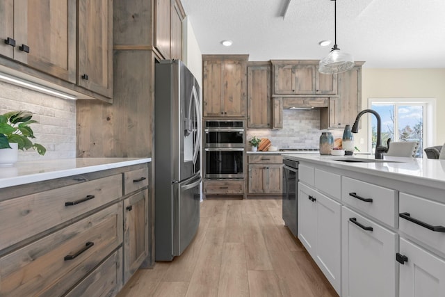 2080 151st Ave NW, Andover, MN 55304 - kitchen featuring stainless steel appliances, a sink, decorative backsplash, hanging light fixtures, and light wood-style floors