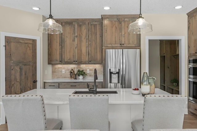 2080 151st Ave NW, Andover, MN 55304 - kitchen featuring stainless steel fridge, a sink, decorative backsplash, a center island with sink, and pendant lighting