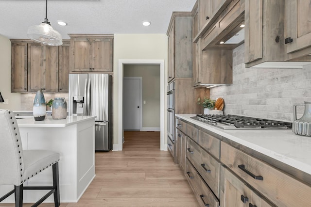 2080 151st Ave NW, Andover, MN 55304 - kitchen featuring appliances with stainless steel finishes, light countertops, tasteful backsplash, pendant lighting, and light wood finished floors