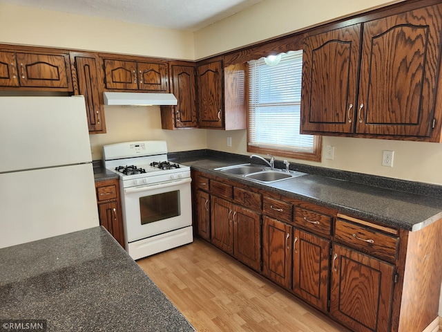 kitchen featuring a sink, white appliances, dark countertops, and under cabinet range hood