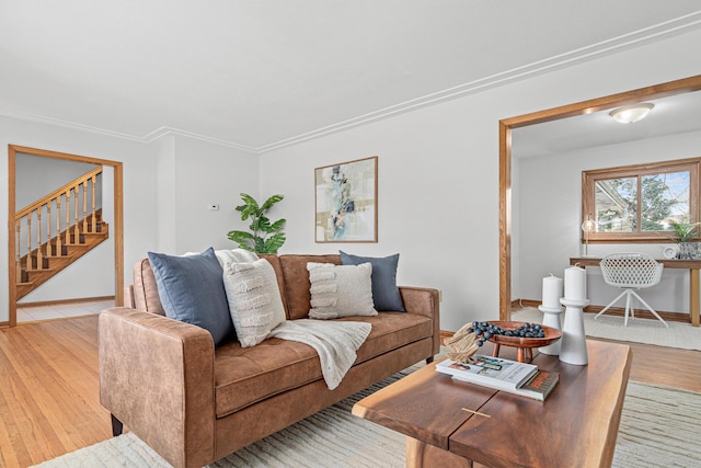 living room featuring crown molding, stairway, baseboards, and light wood-type flooring