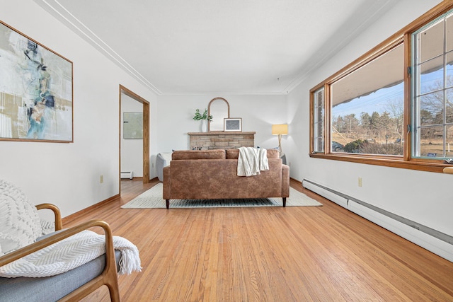 living area with light wood-type flooring, baseboard heating, and ornamental molding