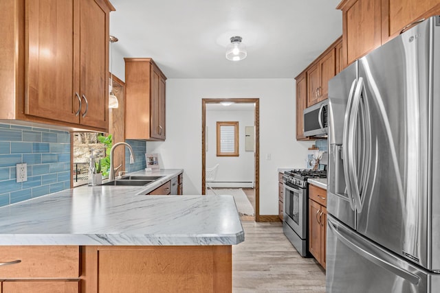 kitchen with brown cabinets, a sink, stainless steel appliances, a baseboard radiator, and decorative backsplash