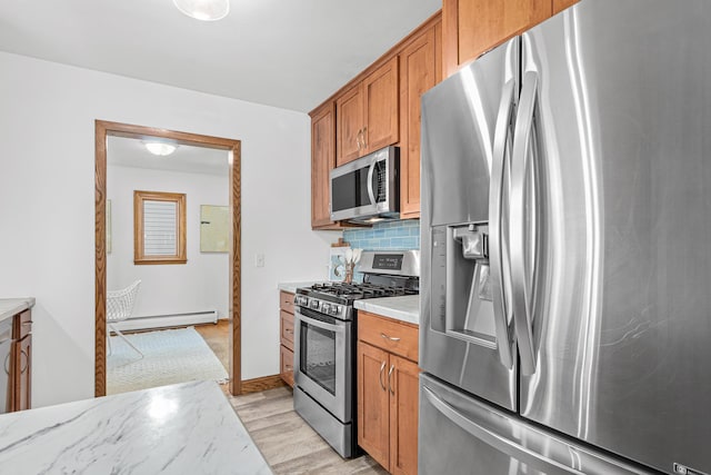 kitchen with tasteful backsplash, light wood finished floors, appliances with stainless steel finishes, brown cabinetry, and a baseboard radiator