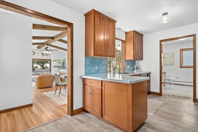 kitchen with decorative backsplash, light wood-type flooring, a wealth of natural light, and a sink