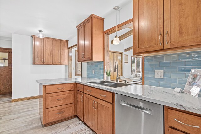 kitchen featuring brown cabinetry, a peninsula, a sink, stainless steel dishwasher, and backsplash